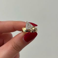 a woman's hand holding a gold ring with a pear shaped diamond on it