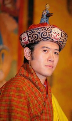 a man wearing a colorful hat with skulls on it's head and an elaborately decorated top