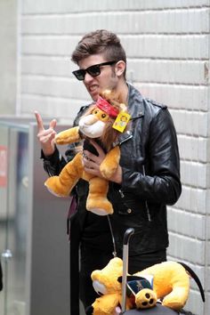 a man in black jacket holding two stuffed animals