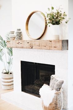 a living room with a fireplace, mirror and potted plants on the mantel