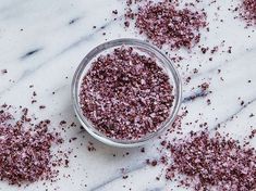 a glass filled with pink glitter next to a banana on a marble counter top,