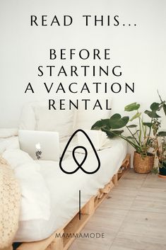 a bed sitting next to a plant and a laptop on top of a wooden table