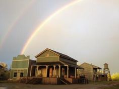 two rainbows are in the sky over a house with stairs and steps leading up to it