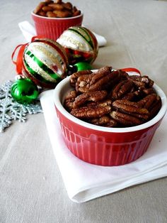 two red dishes filled with pecans sitting on top of a white cloth covered table