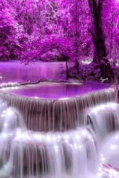 a waterfall with purple trees in the background and water flowing down it's sides