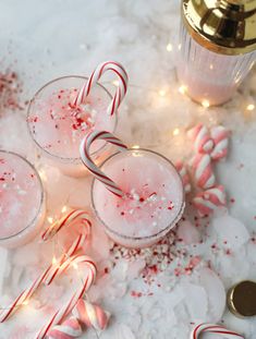 three glasses filled with candy canes and peppermint on top of snow covered ground