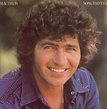 a man with curly hair smiling and wearing a blue shirt on the cover of a magazine