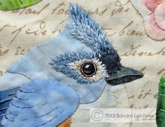 a blue bird sitting on top of a piece of fabric next to flowers and leaves