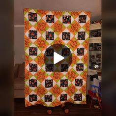 an orange and green quilt hanging on a wall in a living room with the video showing it