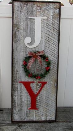 a wooden sign that says joy with a wreath and bow hanging on the front of it