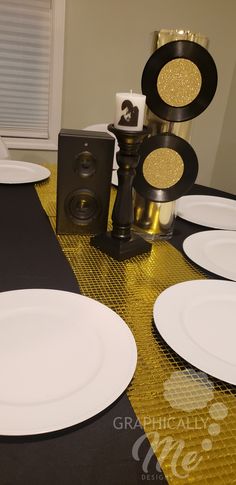 white plates and black speakers on a table with gold foiled paper placemats