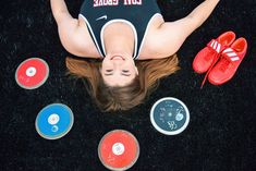 a woman laying on the ground surrounded by various colored discs and slippers, with her eyes closed