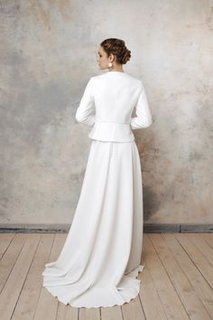 a woman in a white dress standing on a wooden floor with her back to the camera