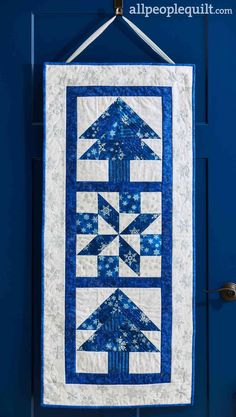 a blue and white quilt hanging on a door with an arrow in the center that has snowflakes all over it