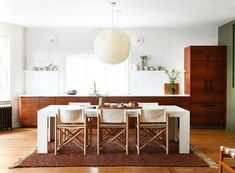 a table and chairs in a room with wood flooring, white walls and cabinets