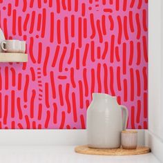 a white vase sitting on top of a counter next to a pink wall