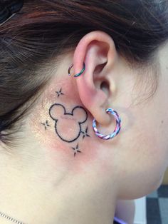 a woman with a mickey mouse ear tattoo on her left side behind the ear is a small hoop