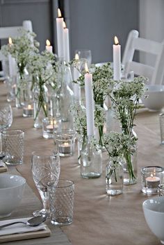 the table is set with candles and vases filled with baby's breath flowers