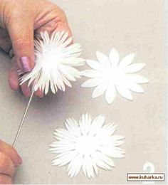 someone is making paper flowers out of white paper and threading them together with scissors