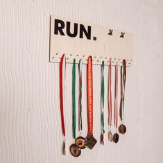 a sign that says run with medals hanging from it's side on a wall