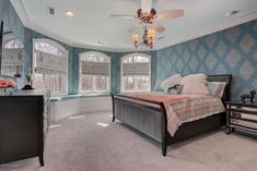 a bedroom with blue walls and carpeted flooring has a large bed in the center