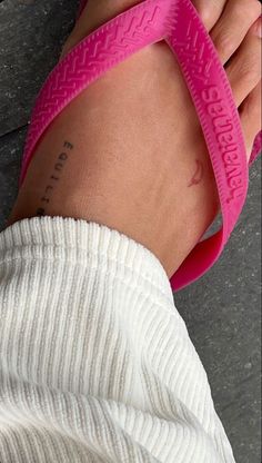 a woman's foot with a tattoo on her left leg and pink sandal