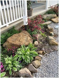 a garden with rocks and flowers next to a house