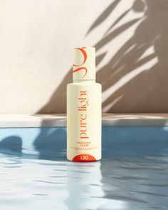 a bottle of sunscreen sitting on top of a swimming pool next to a wall