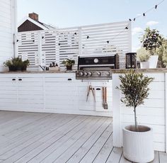 an outdoor kitchen with potted plants on the counter and grill in the back yard