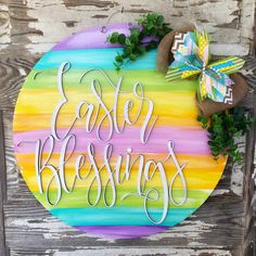 a colorful painted sign that says easter blessing on the side of a wooden door with a bow