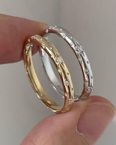 two gold wedding rings with diamonds on each one being held in someone's hand