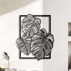 a white wall with a black frame and some plants on it