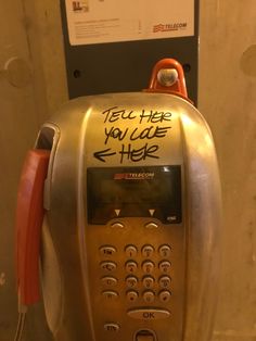 an old style pay phone with graffiti on it