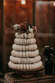 a stack of macaroons sitting on top of a wooden table next to vases