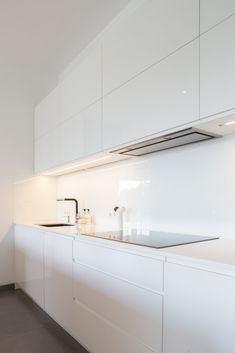 a kitchen with white cabinetry and counter tops is seen in this image from the side