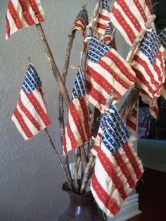 a vase filled with red, white and blue flags on top of a wooden table