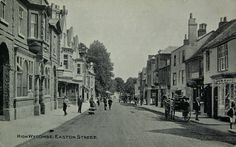 an old black and white photo of people walking down the street with horse drawn carriages