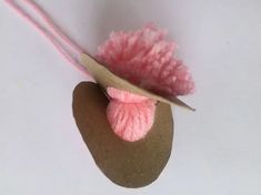 a pink pom - pom hat on top of a rock next to a pair of scissors