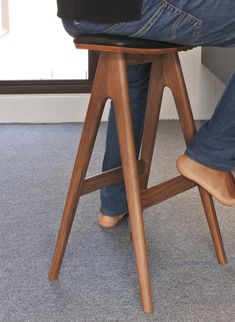 a person is sitting on a stool with their feet propped up against the chair legs