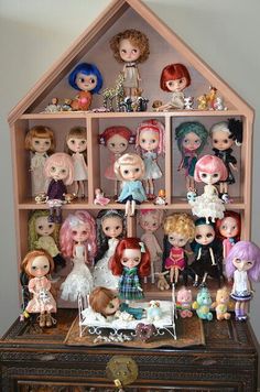 a collection of dolls sitting on top of a wooden shelf