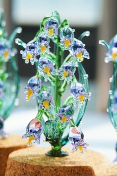 three small glass vases sitting on top of wooden bases with flowers in the middle