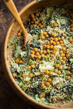 a wooden bowl filled with broccoli, chickpeas and other food items