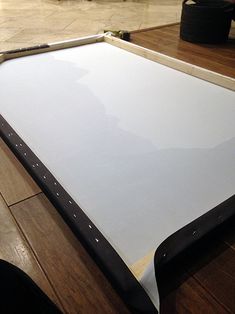 a large white board sitting on top of a wooden table next to a black bag