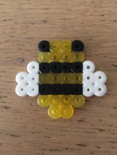 a yellow and black bee brooch sitting on top of a wooden table