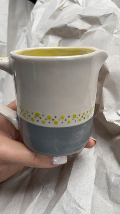 a hand holding a coffee cup with yellow dots on it