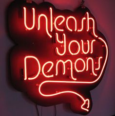 a red neon sign that says, unleash your demon on it's side