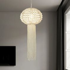 a white chandelier hanging from the ceiling in a room with grey walls and windows