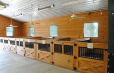 the inside of a horse barn with wooden stalls