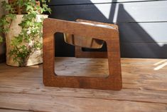 a wooden object sitting on top of a wooden table next to a potted plant