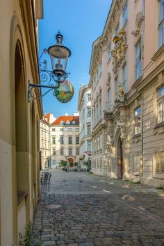 an empty cobblestone street lined with old buildings in the city, during the day